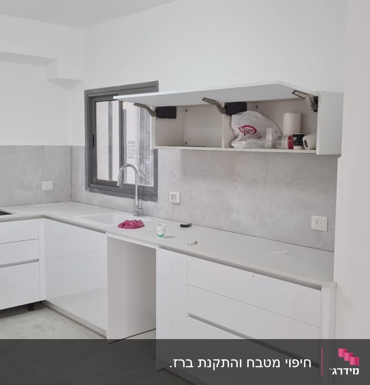 מטבח בשיפוץ עם ארונות פתוחים ומשטח עבודה